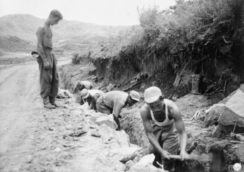 Four men of the Korean Service Corps redigging a monsoon drainageditch along a road leading to The H