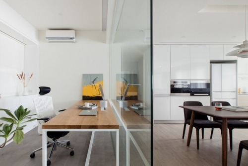 A glass partition separates this minimal workspace from the kitchen. This gives the feeling of open 