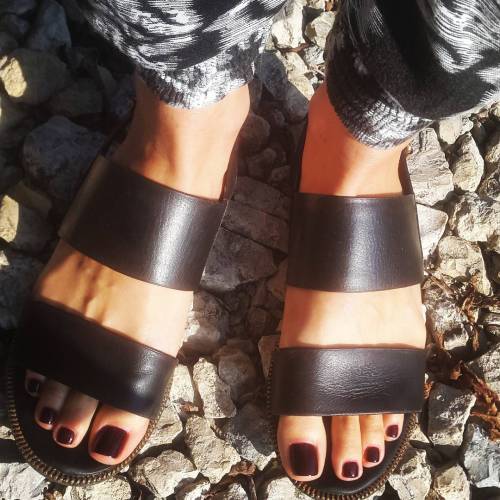 Wide banded brown leather sandals on pretty feet.