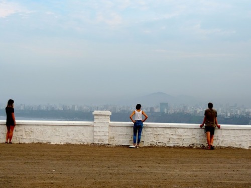 En una brumosa mañana de finales del verano, tres turistas que miran la vista de Lima desde el monum