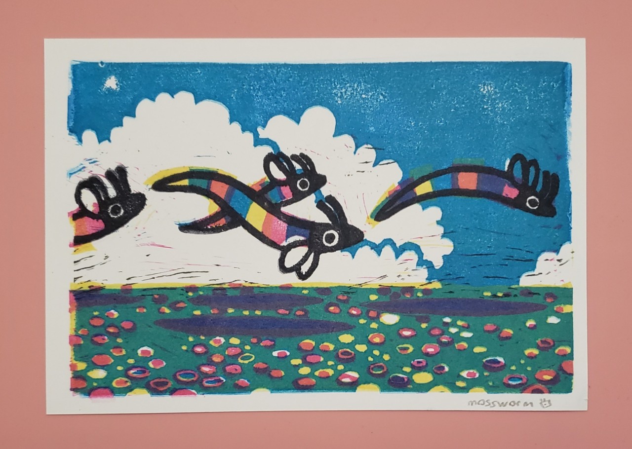 landscape with blue sky, white clouds, green grass and multi colored flowers. in the air are four rainbow colored serpent creatures with small wings, flying close to the ground in a group