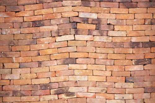 thedesigndome:  A Single Book Can Alter The Strongest Of Foundations Installation artist Jorge Mendez Blake creates a powerful brick sculpture titled “The Castle”. The intimidating wall, formidable and erect, loses its symmetry and forms a rift at