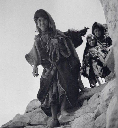 Algeria. Young Amazigh Chaoui woman carrying a goatskin called guerba and coming back from the villa