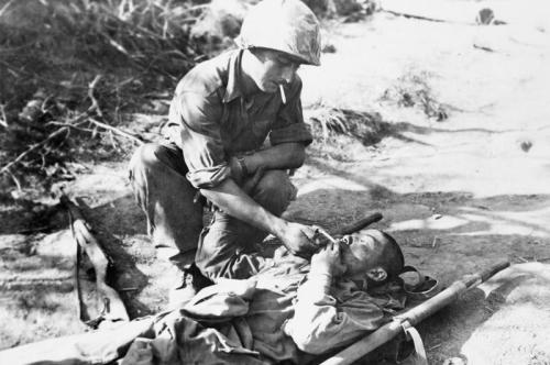 demons:Sgt Roger Pouit, of the French force, helps a wounded North Korean prisoner light a cigarette