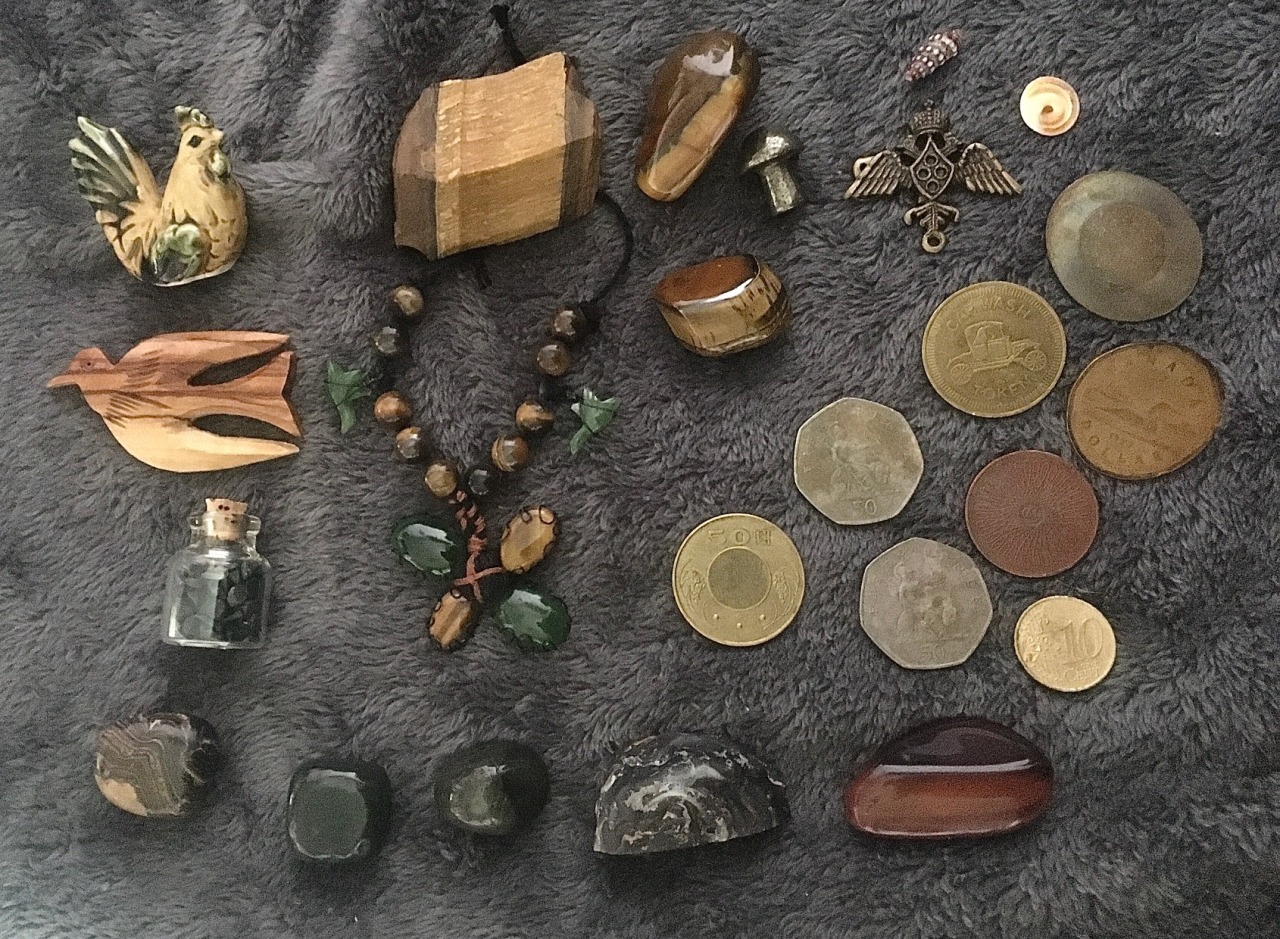 Here’s some of the trinkets that are on my little Hermes altar. A lot of it is kept in a small treasure box since there isn’t much room on the shelf I keep it on. There is also some other stuff not pictured here,  There’s some older, sentimental items, crystals, rocks from outside, coins, shells and jewelry pieces. The wonky-looking bracelet is made by me with tiger’s eye and what I believe are jade beads. I was kind of going for the apperance of a four leaf clover, but it does also kinda look like a flower or something. I don’t actually wear the bracelet though, I just use it as decoration.  #altar#witch#witchcraft#witch altar#my post#my hoard#my photos#crystals#gremlincore#crowcore#corvidcore#gremlin hoard#rock collection#trinkets#crow hoard#rock collecting#forestcore#shinies#crystal collection#hermes#goblincore#hermes altar#hermes deity#goblin hoard#crystal witch#tigers eye#labradorite#geode#mosscore#fairycore