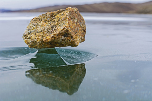 modmad:thisobscuredesireforbeauty: “Baikal Zen”: Rocks that have fallen on the ice of Lake Baikal are heated by sunlight and emit infrared rays that melt the ice below. Once the sun is gone, the ice becomes solid again, creating a small support for