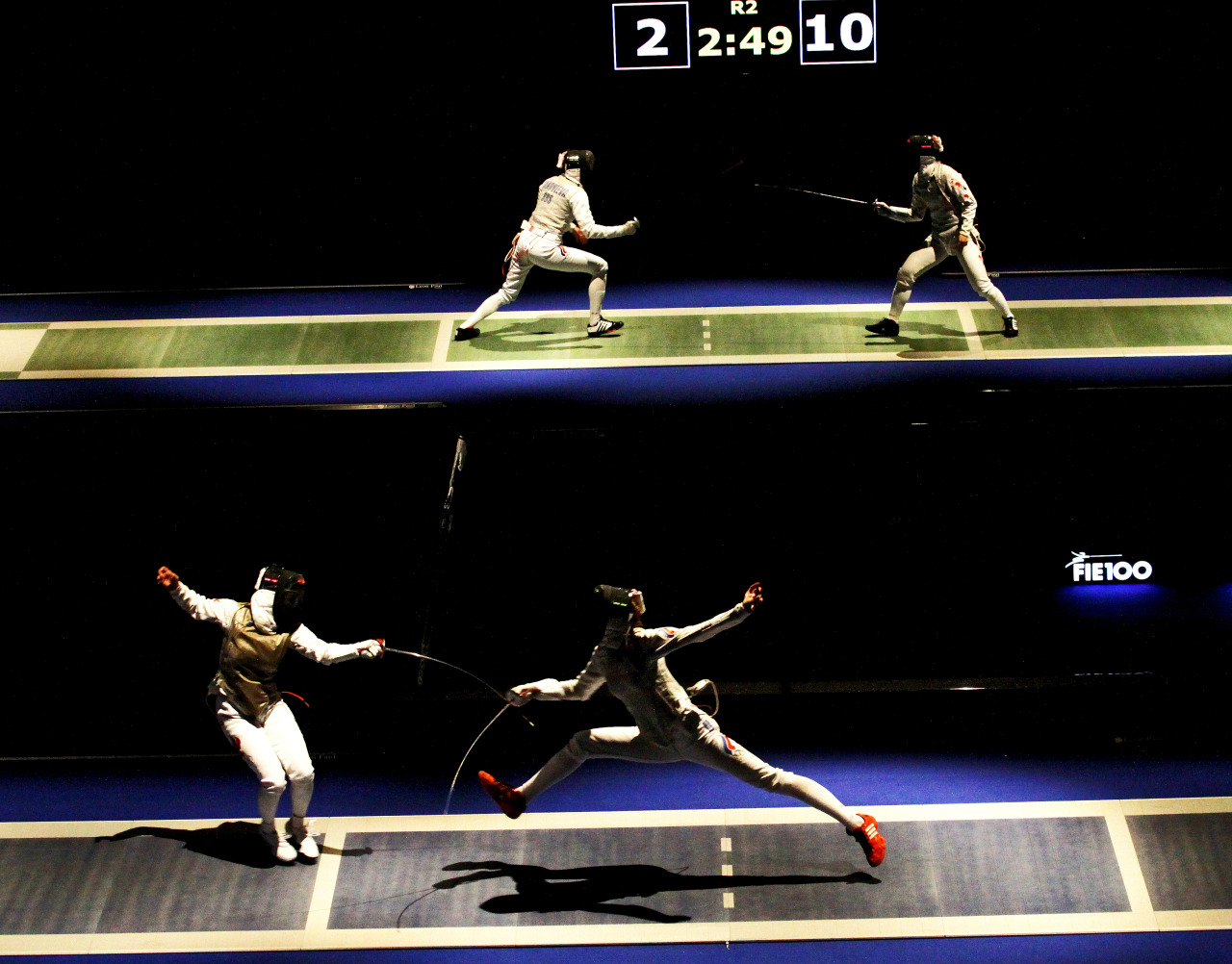 modernfencing:  [ID: a photo of two foil bouts, happening simultaneously on raised