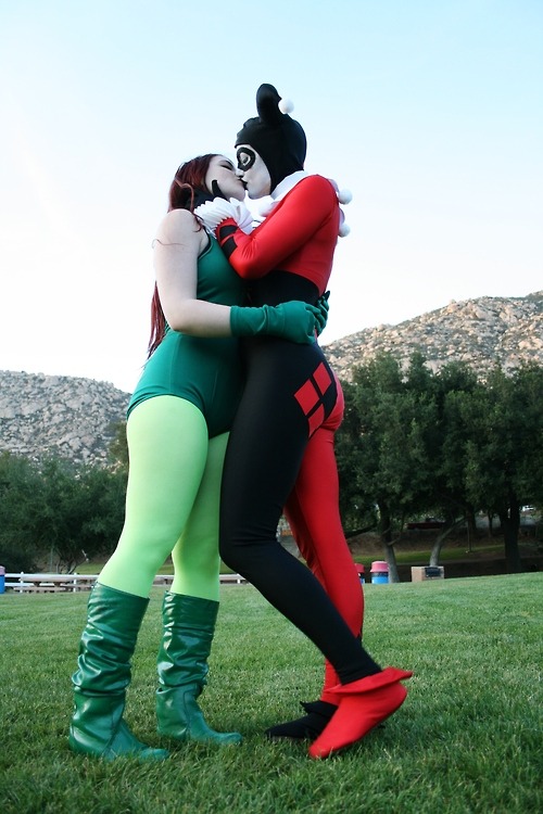 A Poison Ivy cosplayer in green tights partakes in a loving smooch with a Harley Quinn from Love Bir