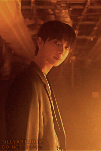 Kanghyun lit by orange light looking down at the camera