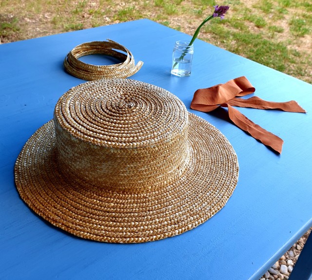 a picture of a blue table, straw boater sunhat and original ribbon and leftover lace next to it. 