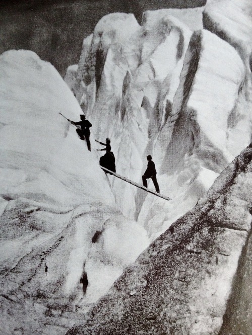 Late Victorian mountaineers, including a lady fully dressed and corseted, cross a crevasse in the Al