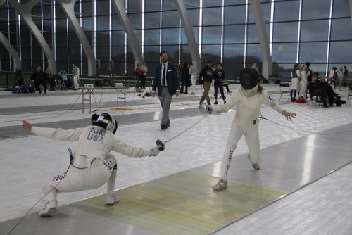 [ID: an epee fencer crouching and hitting her opponent’s hand.]Fencing at the 2018 Remenyik!