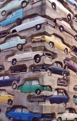ymutate:Armand Pierre Fernandez : Long Term Parking, 1982.This 60 feet (18-meter) high sculpture consists of sixty mostly French cars set in 40,000 pounds (18,000 kg) of concrete. It was created in 1982 by a French-born American artist named Armand Pierre