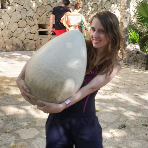 A woman holding a large egg in her arms. Xcaret, Mexico.