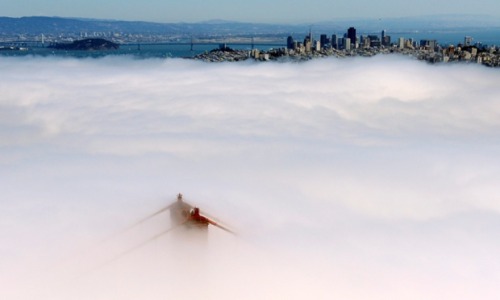 The south tower of the Golden Gate Bridge peers through the fog with San Francisco Oakland Bay Bridg