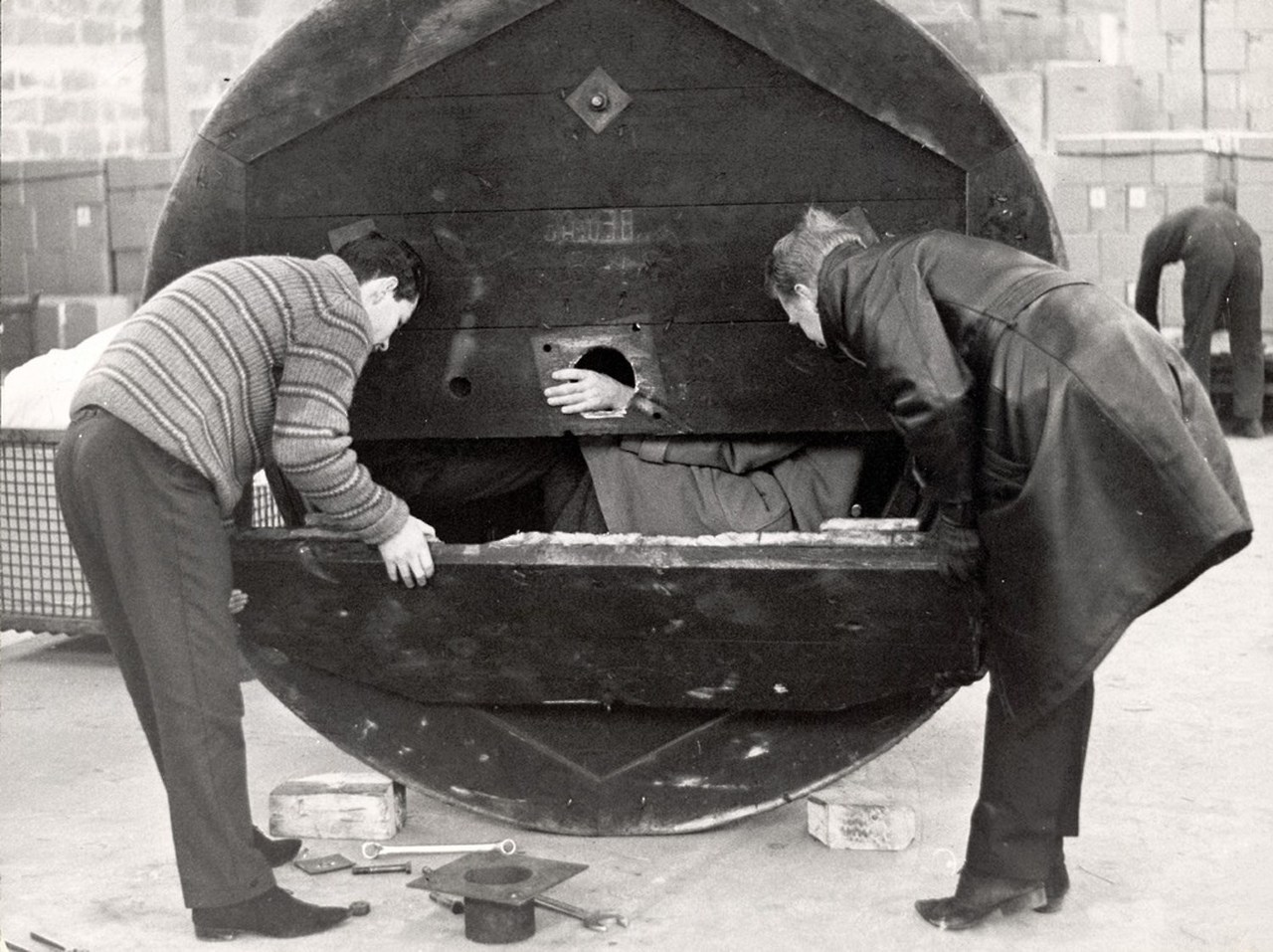  Two men open a hollow metal drum used by three West German men to bring their girlfriends