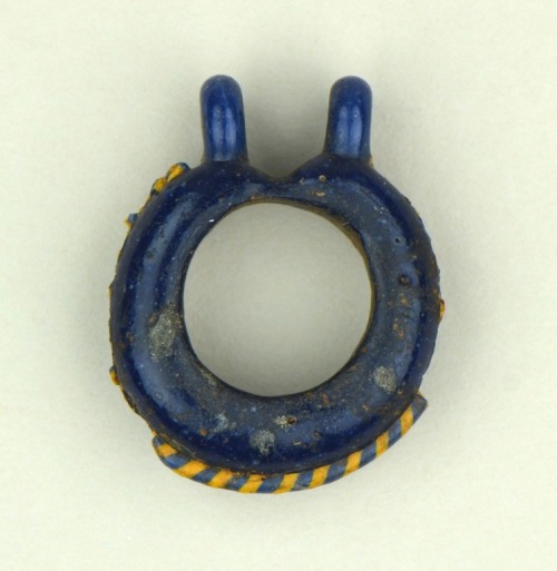 One of a pair of ancient Egyptian deep blue glass earrings featuring a yellow and light blue twist o