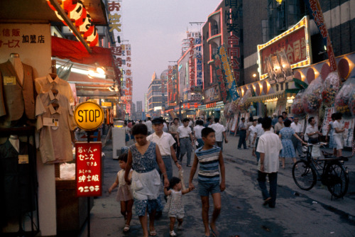 Shoppers fill Tokyo’s neon-lit shopping district at twilight, November 1964.Photograph by Winf