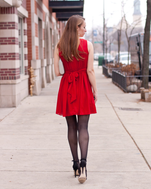 Black polka dot pantyhose, high heels and pleated red dress with bow on the back