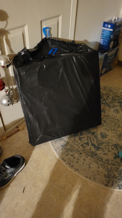 A full black trash bag that is suspiciously square.