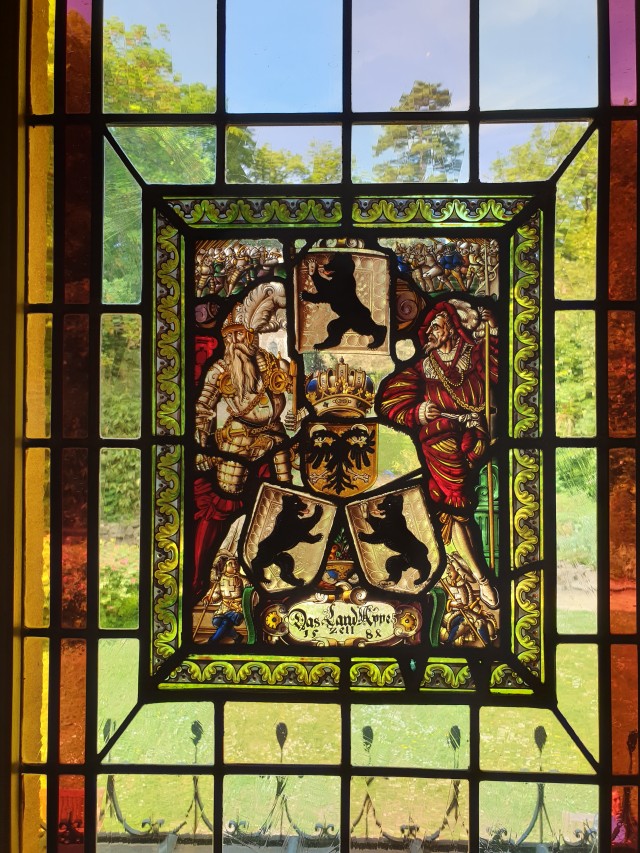 a stain glass window depicting landsknechten in bright colours