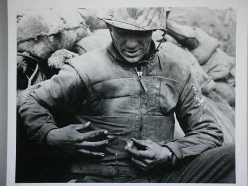 A grateful Marine showes the piece of shrapnel that lodged in his armored vest instead of his stomac