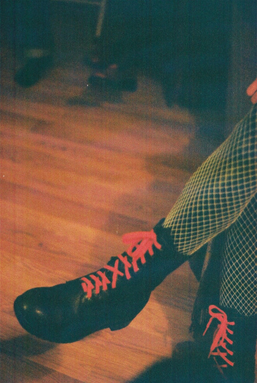 Skin tight vinyl pants with neon yellow fishnets and combat boots with orange laces.