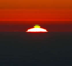 sci-universe:  Green flash is an optical phenomena in which the top edge of the Sun momentarily turns green. It occurs shortly after sunset or before sunrise. When the sun starts to dip below the horizon the colors of the spectrum disappear one at a time,