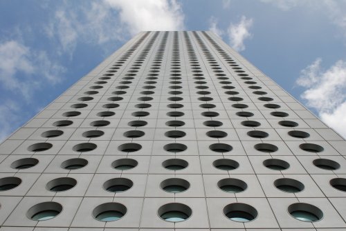 architectureland:  Jardine House  - Palmer & Turner The building is constructed with a metal frame, and a curtain wall with round windows. The thickness of the structural frame is reduced because of the shape of the windows. Unusually for a Jardine