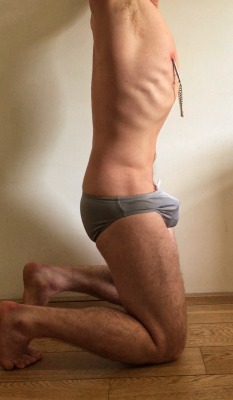 tightlypacked:  boy working on his kneeling posture… waiting patiently in grey speedo and holy trainer v2 small. talon nipple clamps, of course.