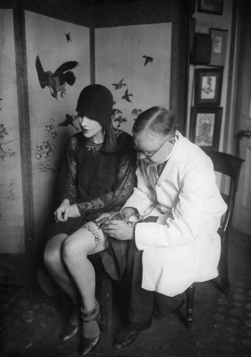 maudelynn: Flapper getting a Garter tattooed on her leg c.1926  original via http://head-heart-health.com 