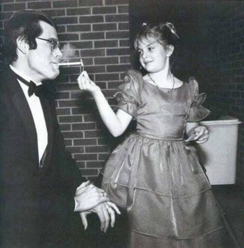 coolkidsofhistory: Stephen King has his cigarette lit by a young Drew Barrymore, 1984.