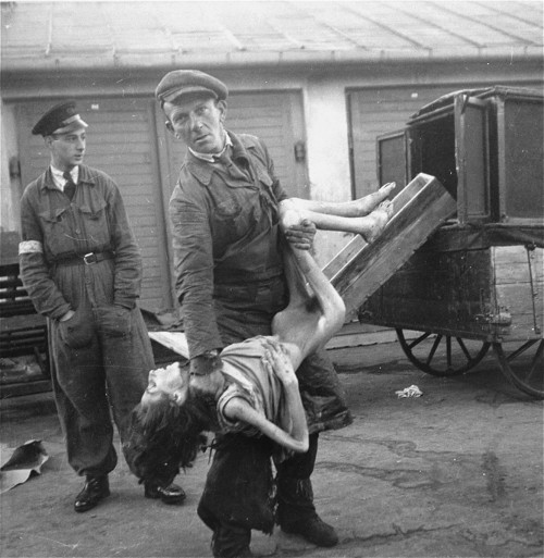 An undertaker in the Warsaw ghetto&rsquo;s Jewish cemetery on Okopowa Street lifts the body of a wom