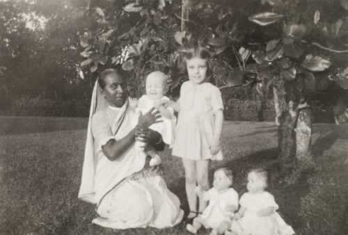 An Indian ayah (nursemaid) poses beside her British charges, a young girl and a baby, in the garden 