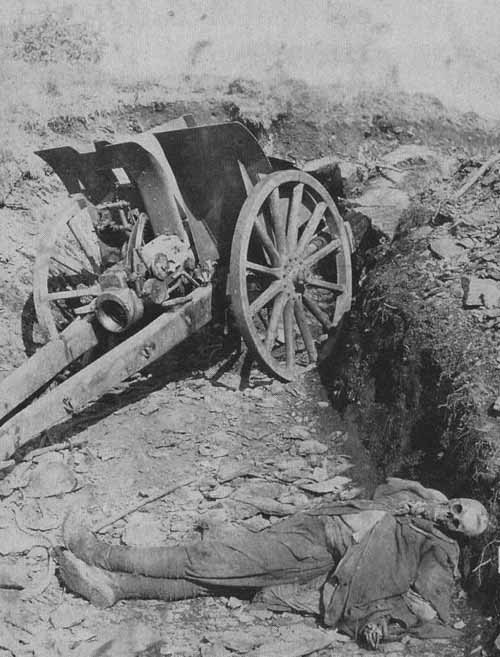 scrapironflotilla: Corpse of a soldier lying next to a destroyed field gun.