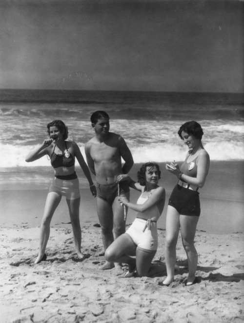 yesterdaysprint: Three women wearing police badges measure the bathing suit of a man on the beach an