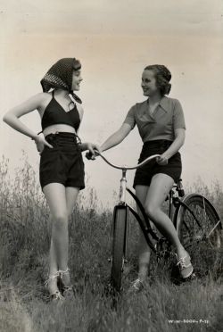 ridesabike:  Libby Harben rides a bike. Ruth Martin wears “a navy gabardine playsuit, trunks and bra-top, and ties her hair peasant fashion, beneath a dotted kerchief.”