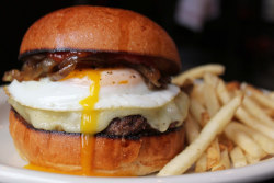 f-word:  burger with bacon jam, gruyere cheese, fried egg, and caramelized onions on a brioche bun with fries photo by a * b
