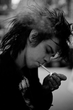 yrmidnightman:  A young Nick Cave lights his cigarette as a cloud of smoke passes through his wild mess of hair—oh, to be so lovely! Photo by Harry Papadopoulos, 1982.  