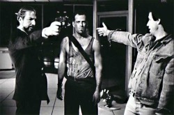 birthmoviesdeath:Director John McTiernan shows Alan Rickman how to point a gun on the set of DIE HARD, 1988.