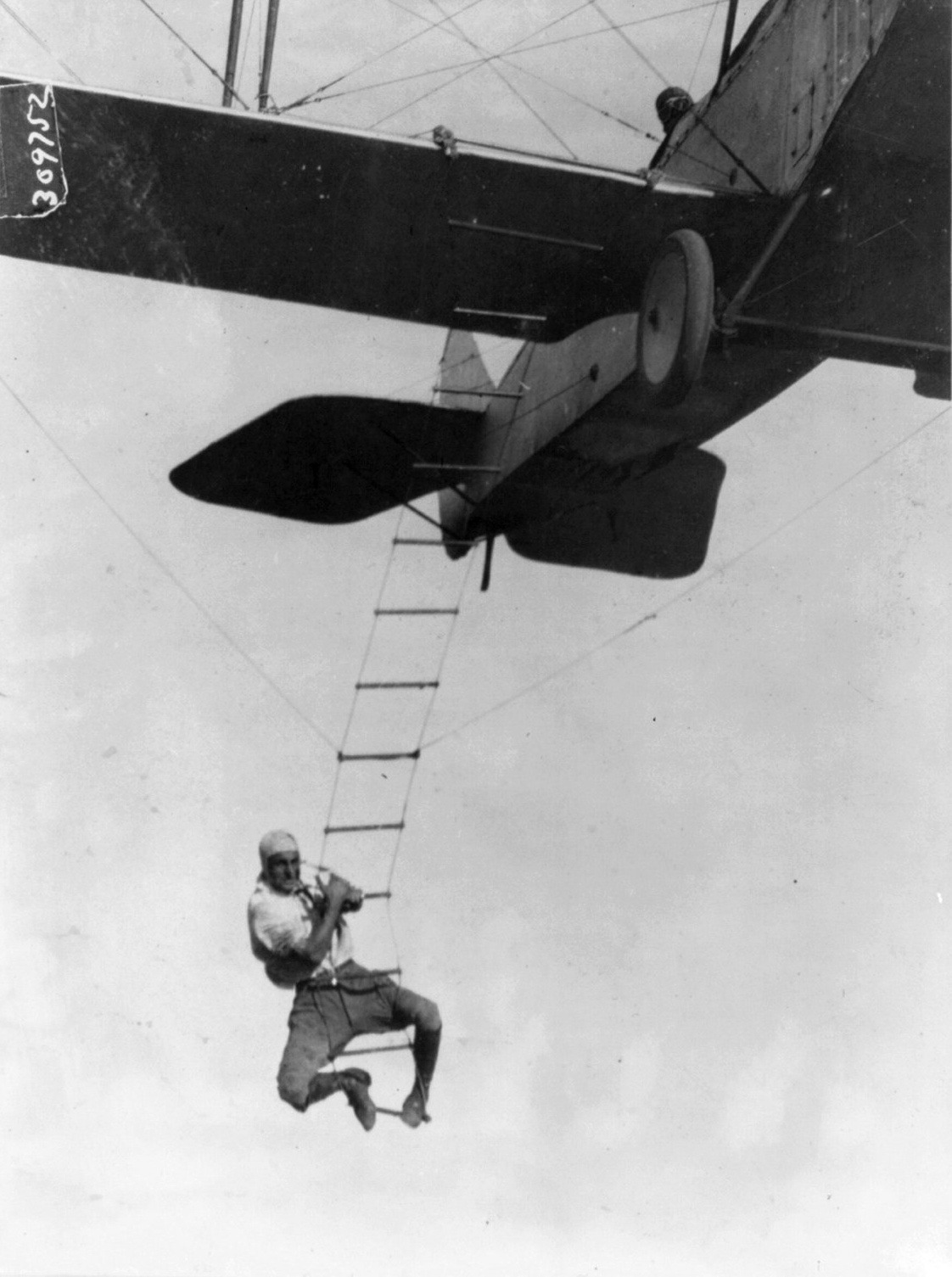 Fearless Freddie, a Hollywood stunt man, clinging to a rope ladder slung from a plane