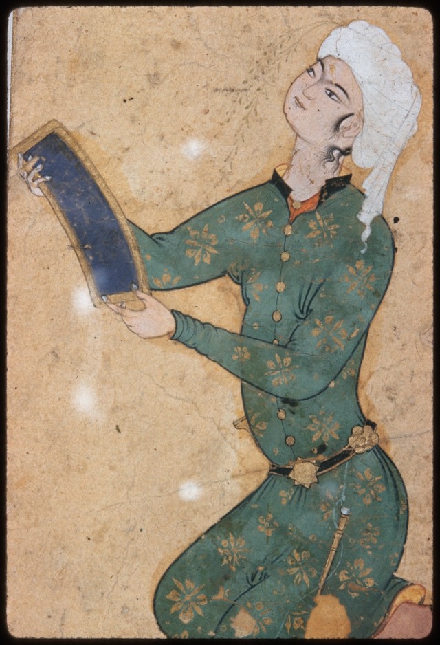 A youth wearing a green robe and a white head turban holding a manuscript.