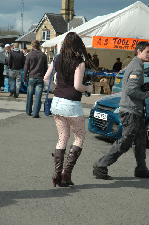 Sexy woman in short denim skirt and black fishnet pantyhose caught in the street. Woman in pantyhose