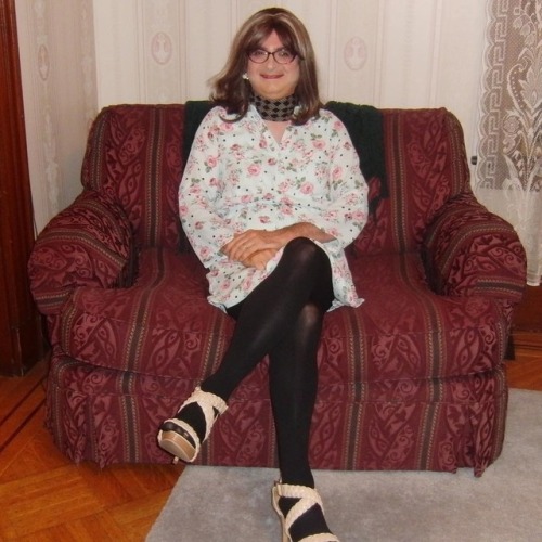 Full-length picture of me, seated, legs crossed, facing forward, wearing my new purple cat-eye glass