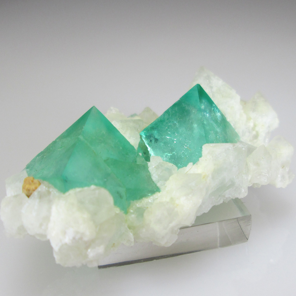 unearthedgemstones:   Two bold neon green octahedral Fluorite crystals sit on a bed