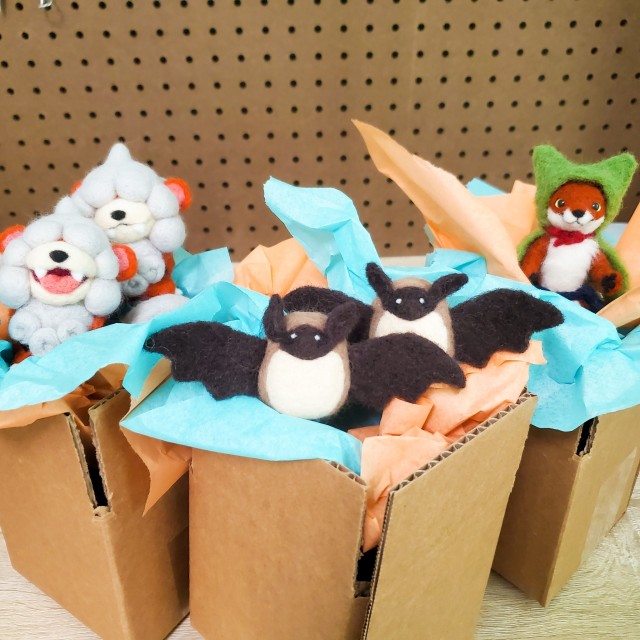 a photo of six needle felted figures in cardboard boxes filled with tissue paper. Two of the needle felted figures are growlithe, a Pokemon. There are also two needle felted bats and a felted fox.