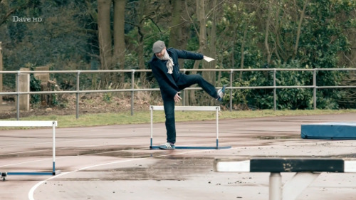 [ID: Five Screencaps Of Dave Gorman On Taskmaster, Traversing An Outdoor Athletics Track With Comically