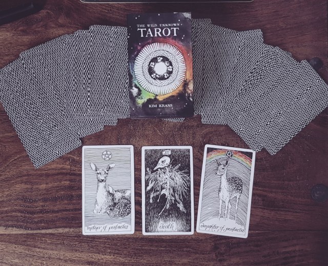 three tarot cards in front of the rest of the deck fanned out upside down