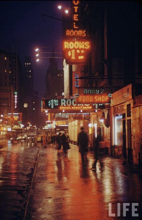 Street scene outside of hotels on east 43rd street by Times Square with neon lights and people walki