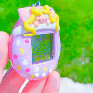 A customized Tamagotchi that resembles the sheets on a bed. Sailor Moon is resting underneath the covers. The covers are pink.